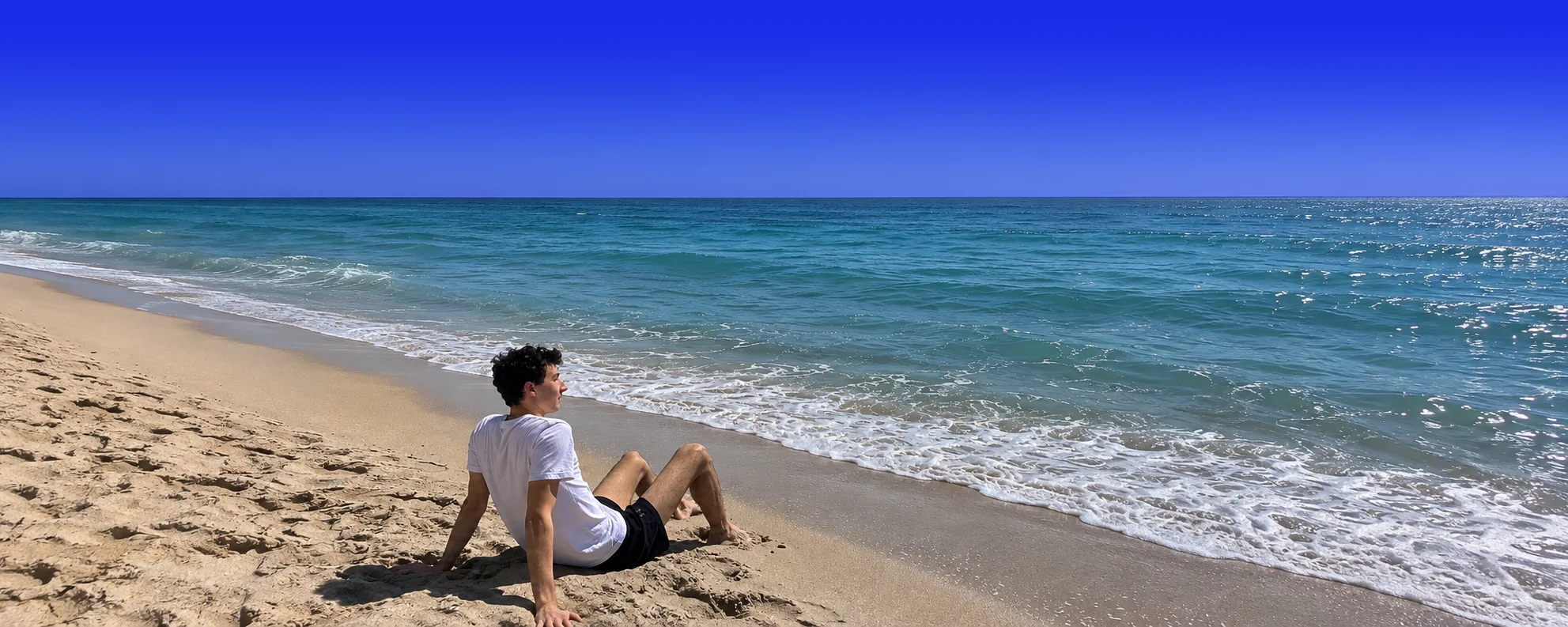 Michael Jacobs sitting on a beach, looking out at the ocean